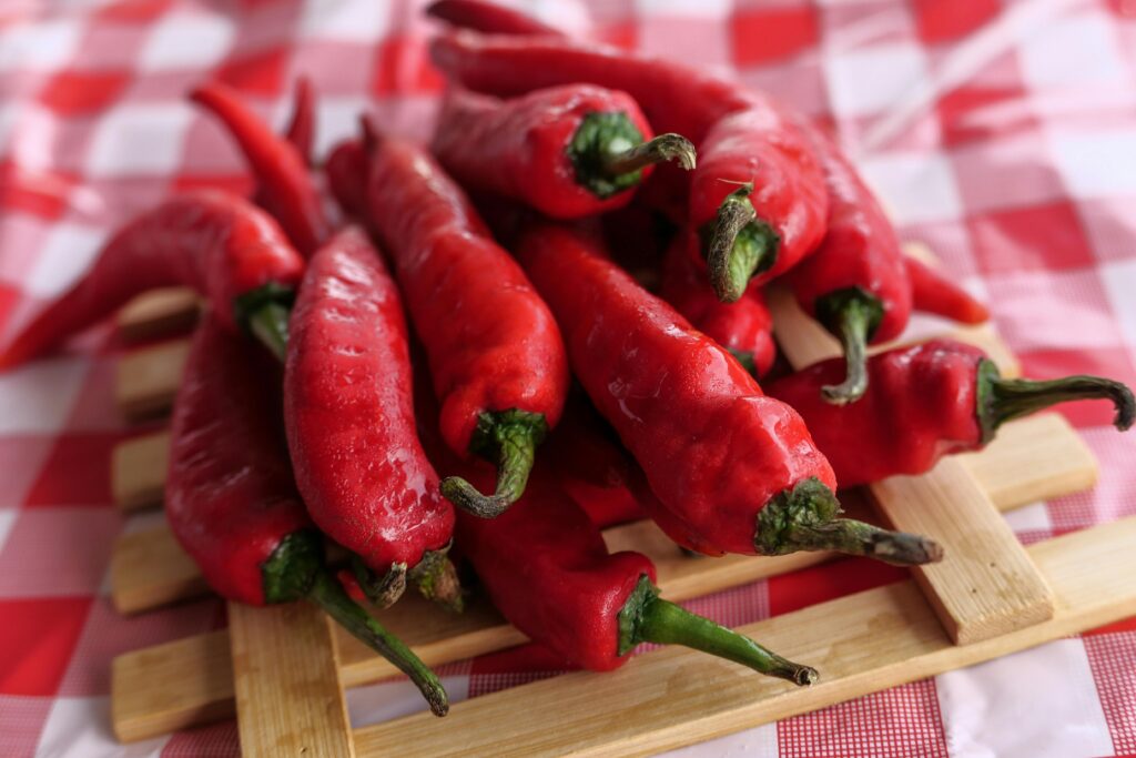 A vivid close-up of red chili peppers on a checkered tablecloth, emphasizing their vibrant color and spicy potential.